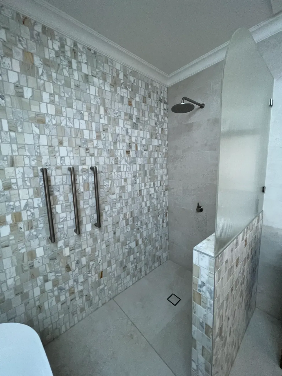 Walk-in shower with mosaic tiles and towel rails