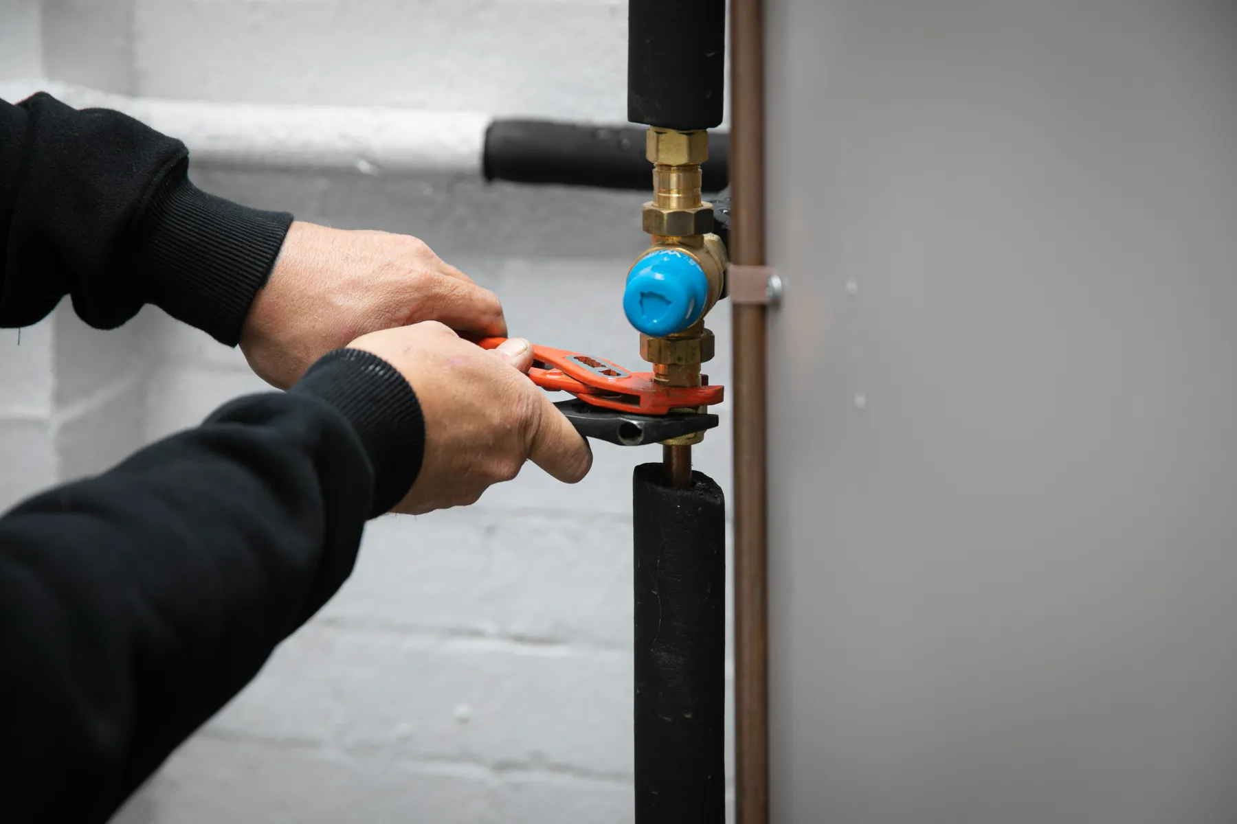 QCore plumber fitting a new valve to a hot water system